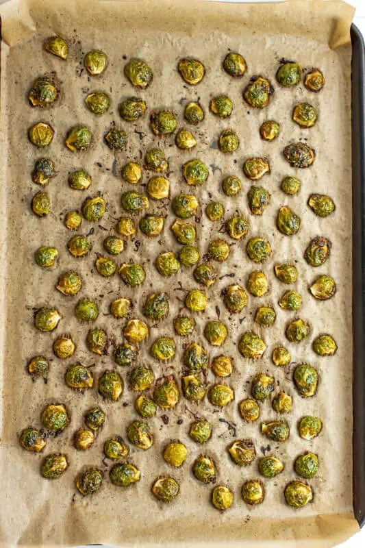 Roasted brussel sprouts on parchment paper lined baking sheet.