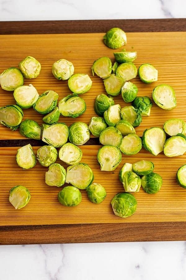 Brussel sprouts cut in half on a wooden cutting board.