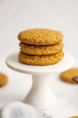 Three gluten free vegan sugar cookies stacked on a small white pedistal.