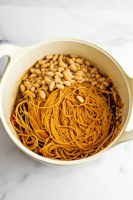 Cooked pasta and white beans added to the pot with the tomato mixture.