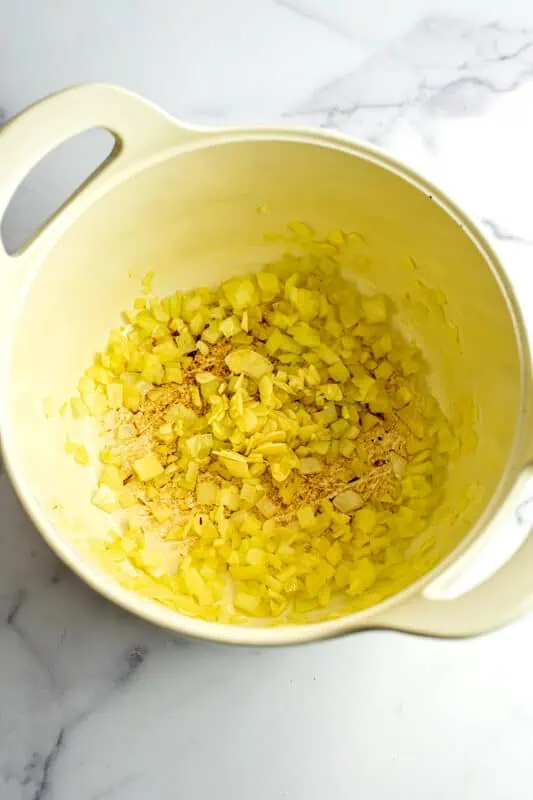 Cooked white onion and garlic in a large white pot.