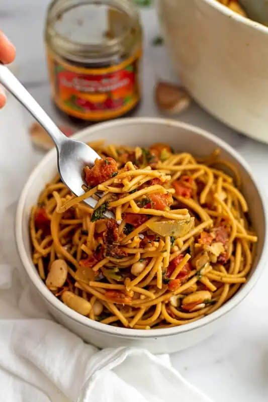 Fork picking up some of the vegan white bean pasta out of a bowl.