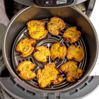 Smashed potatoes in air fryer basket after cooking.