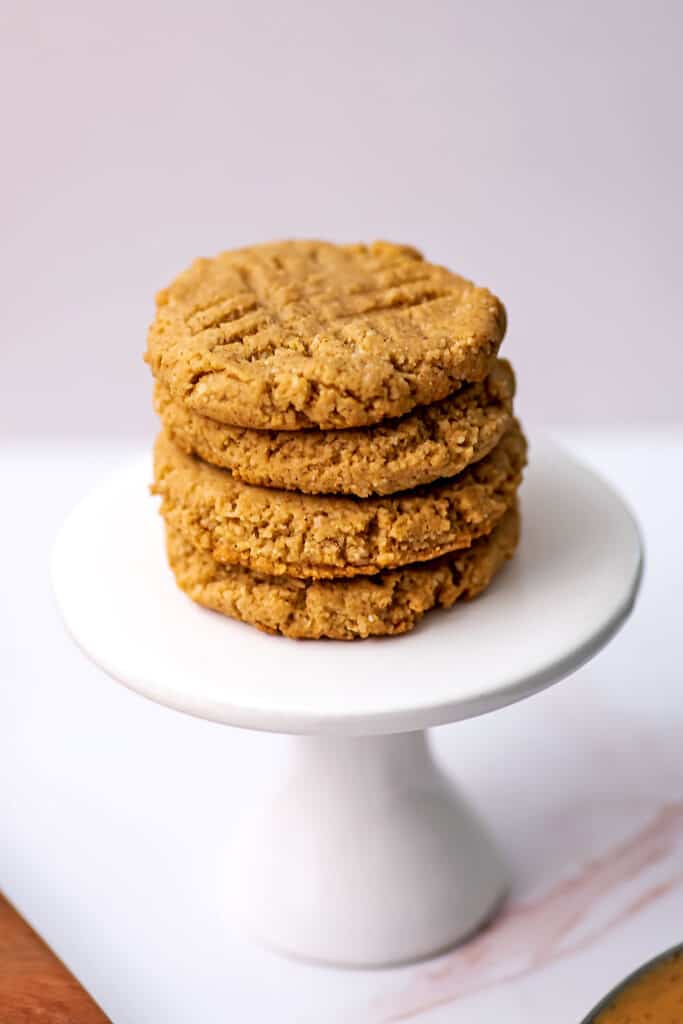 Four almond flour peanut butter cookies stacked on a small pedestal.