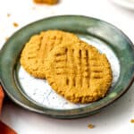 Peanut butter almond flour cookies stacked on a green rimmed plate.