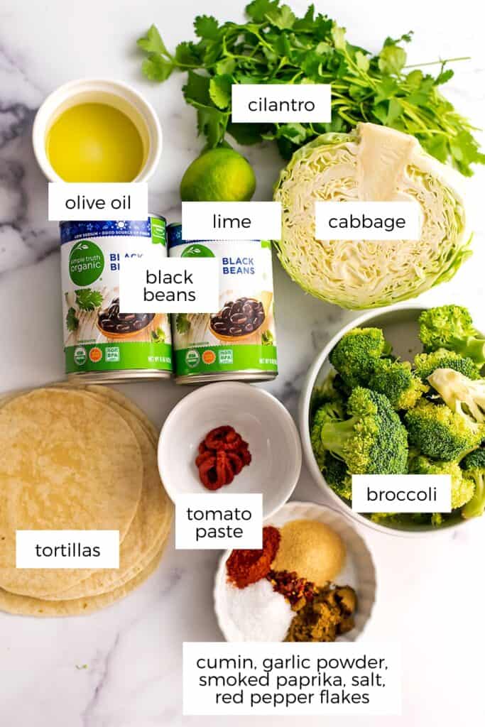 Ingredients to make broccoli tacos in white bowls on marble countertop.