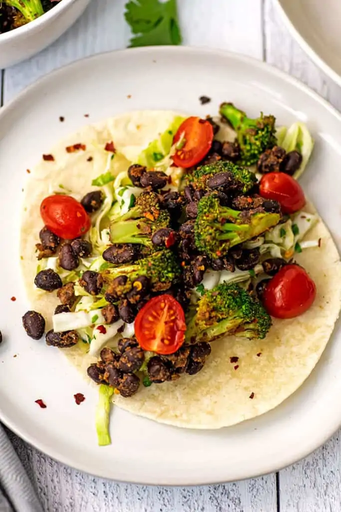 Broccoli black bean taco on a white plate with fork on the side.