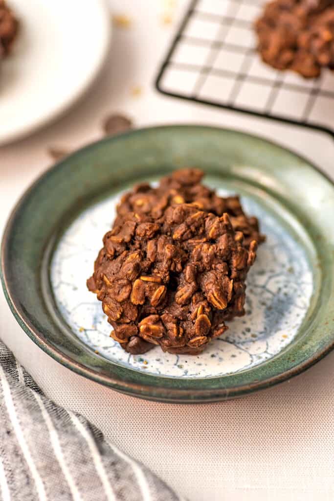 Two chocolate oatmeal cookies on a green rimmed plate.