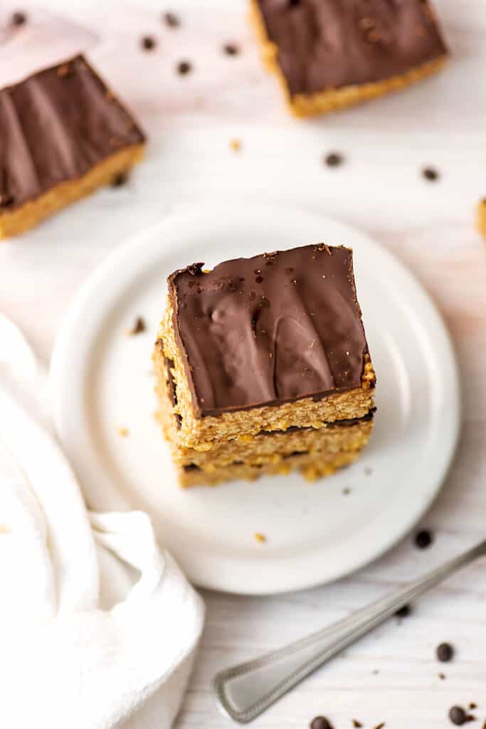 Peanut butter rice krispy treats with chocolate on a white plate, white napkin on the side.