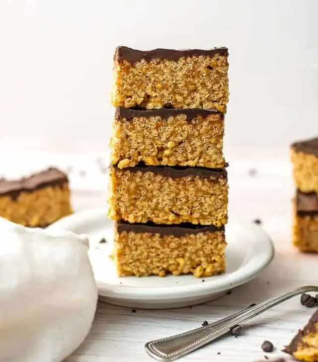 4 chocolate peanut butter rice krispy treats stacked on a white plate.