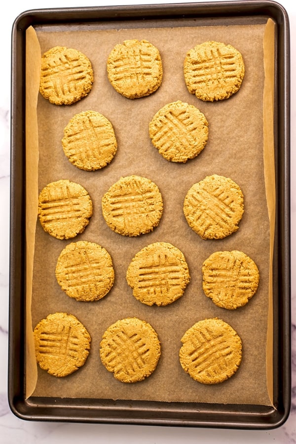 Baked peanut butter almond flour cookies on parchment paper lined baking sheet.