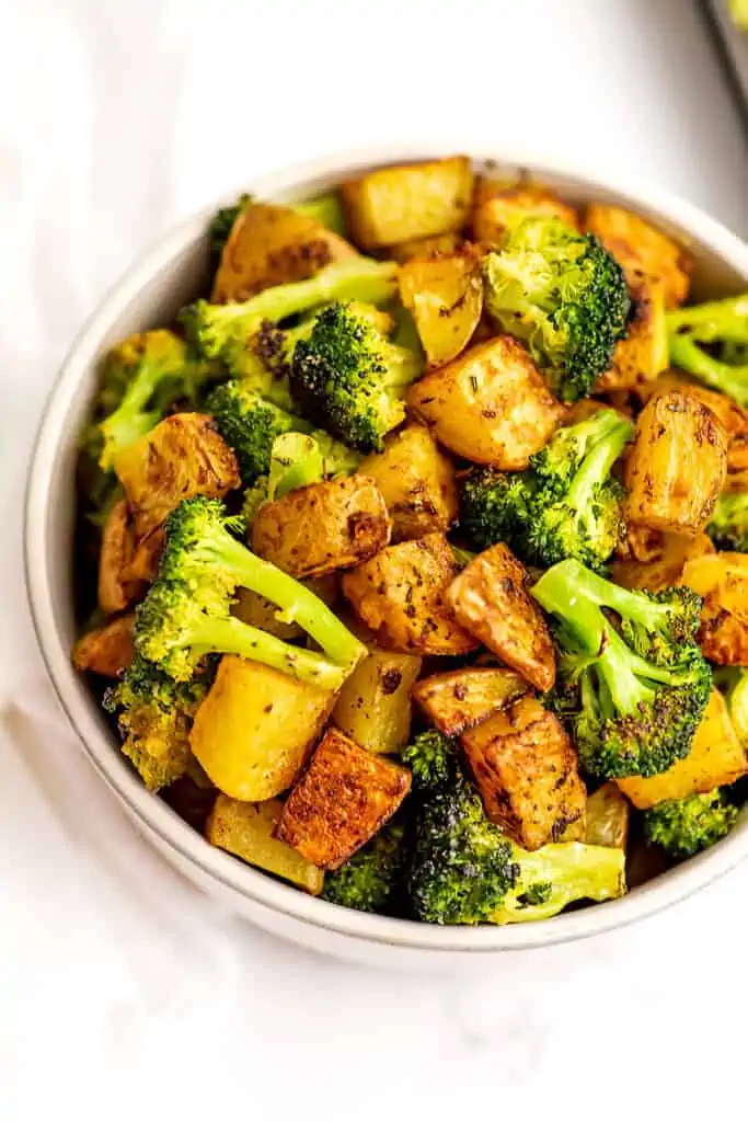 Roasted broccoli and potatoes in a white bowl.
