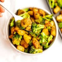 Fork in a bowl filled with roasted potatoes and broccoli.