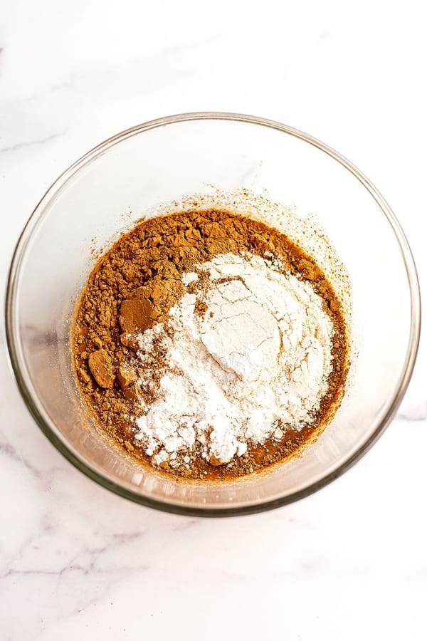Flour and cacao powder added to glass mixing bowl.