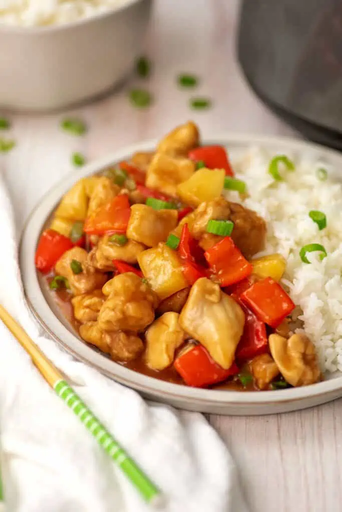 Sweet and sour chicken on a white plate with rice.