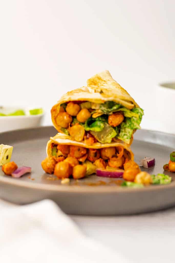 Grey plate with buffalo chickpea wrap cut in half. 