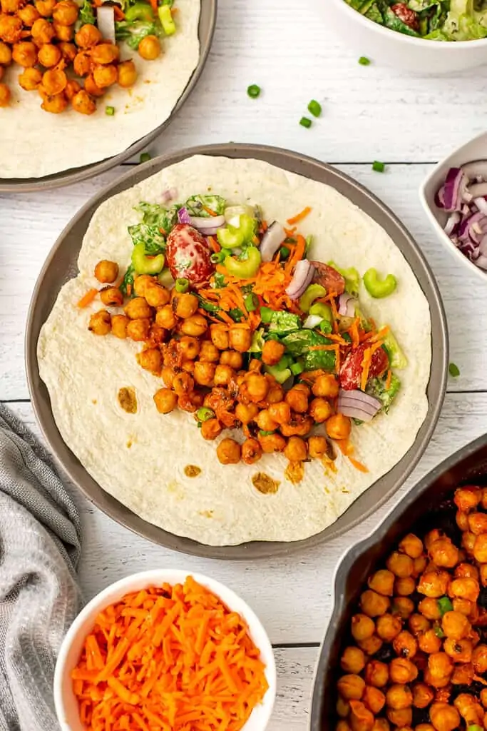 Buffalo chickpeas and veggies on a wrap before wrapping it.