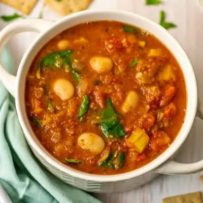 White bowl filled with butter bean stew, with green napkin on the side.