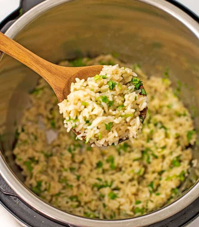 Wooden spoon filled with cilantro lime brown jasmine rice.