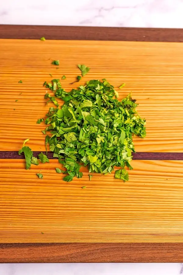 Chopped cilantro on a wooden cutting board.