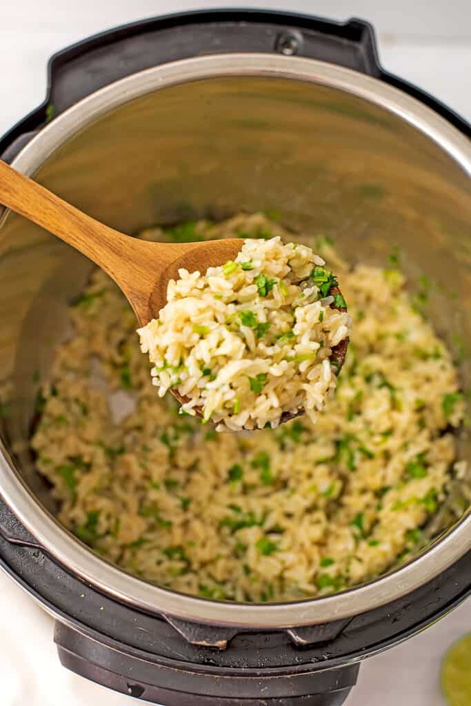 Wooden spoon filled with cilantro lime brown jasmine rice.