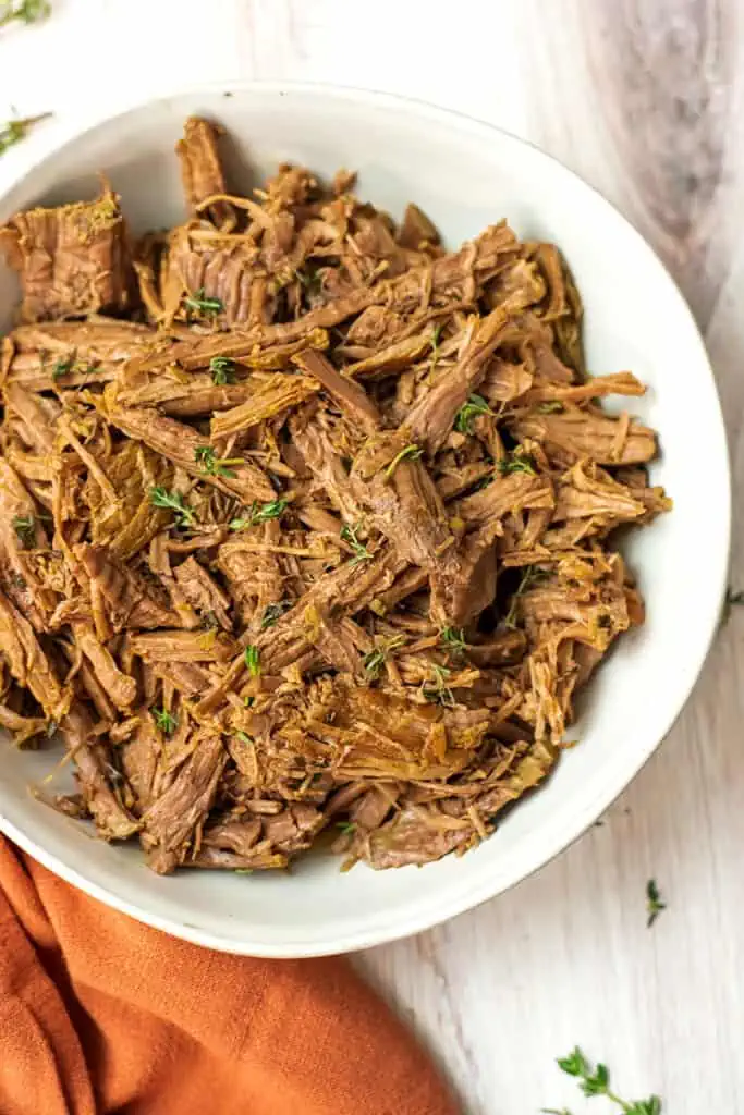 Pulled beef cooked in the instant pot with an orange napkin on the side.