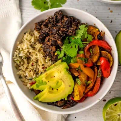 Large white bowl filled with vegan fajita ingredients, fork on the side.