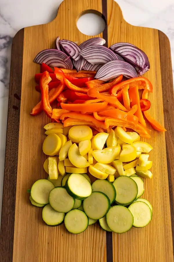 Sliced vegetables on a wood cutting b oard.