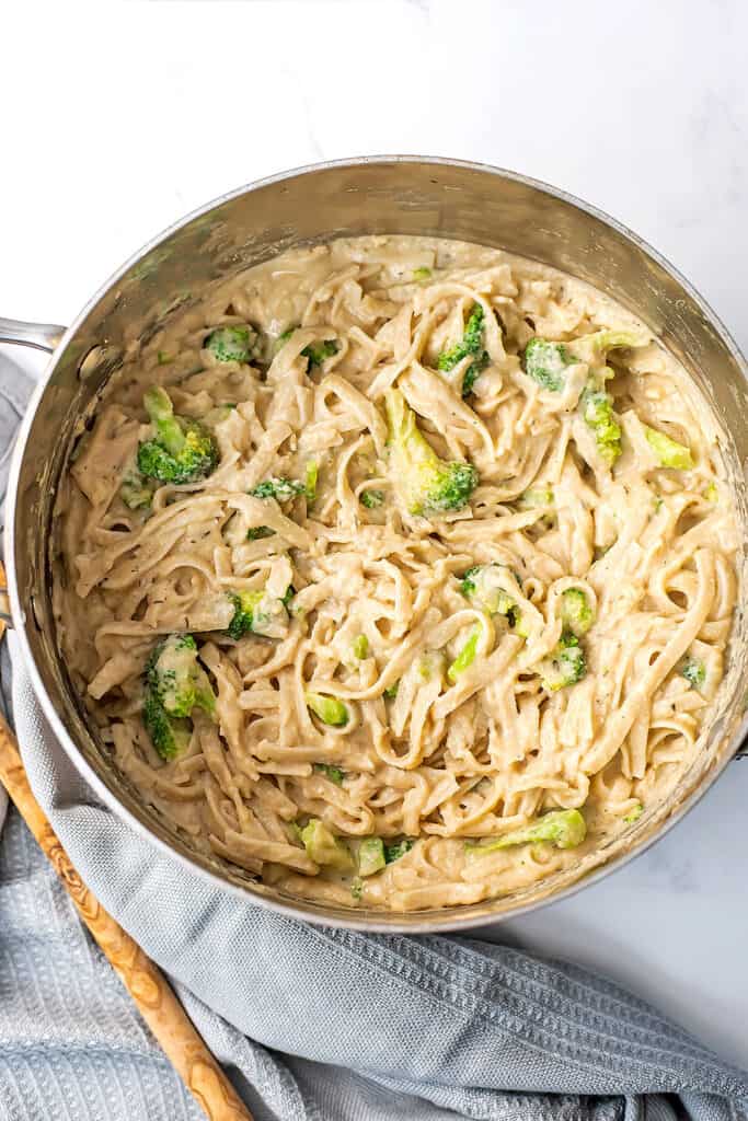 Large pot filled with white bean alfredo pasta with wooden spoon on the side.