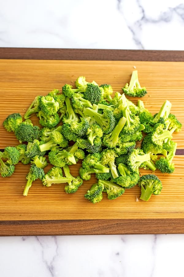 Chopped broccoli on a wooden cutting board.
