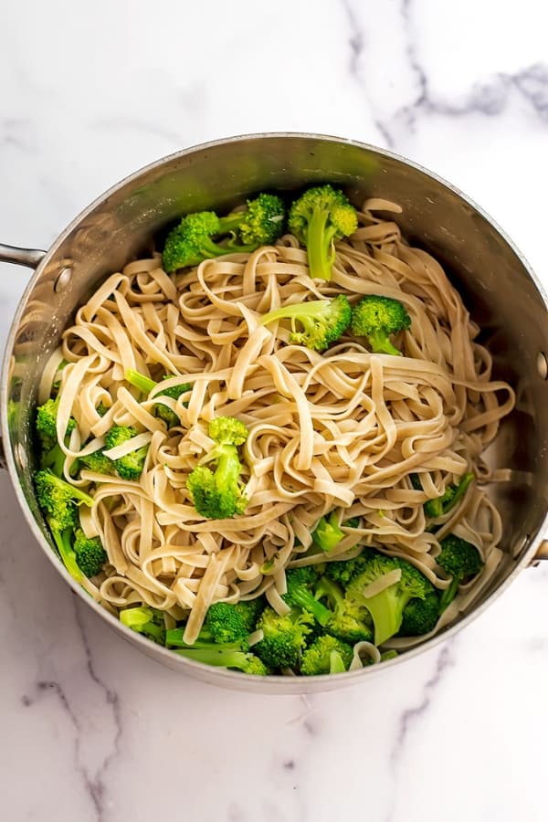 Fettucine and broccoli in a large stainless steel pot.