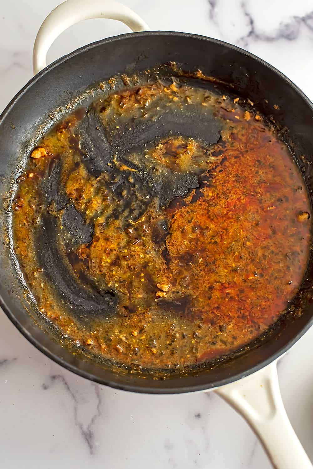 Buffalo sauce in cast iron skillet before reducing.