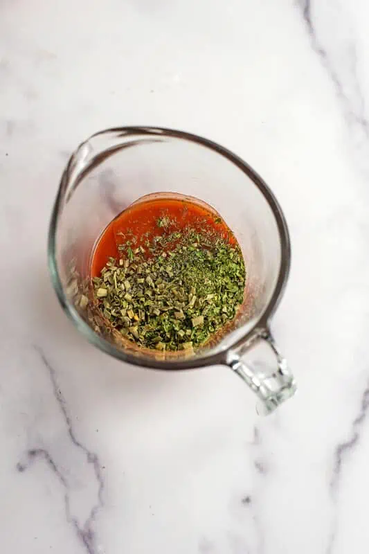 Ingredients to make buffalo sauce in glass measuring cup.