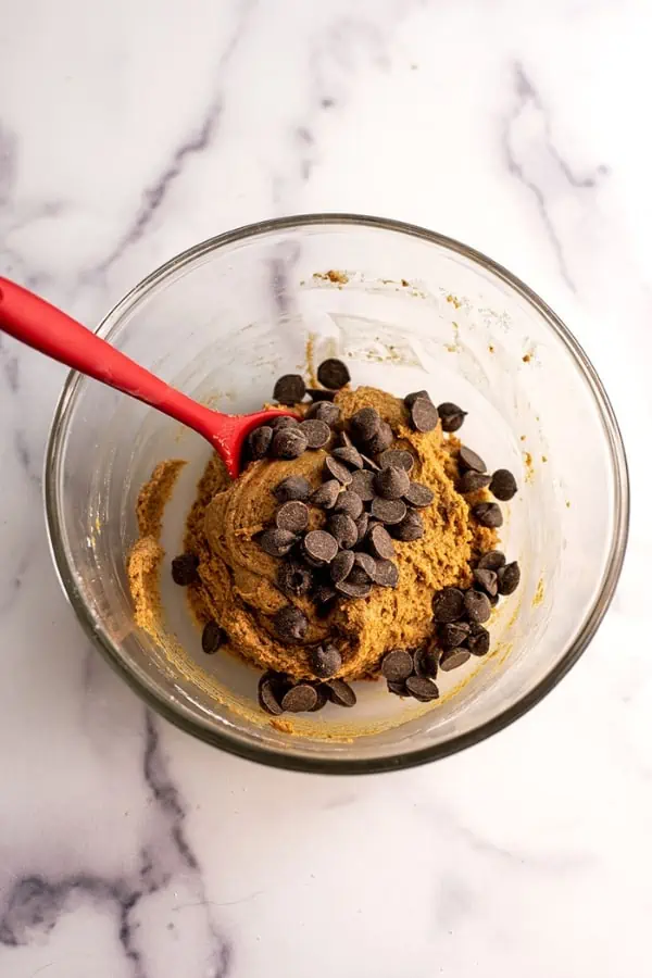 Chocolate chips added to bowl with cookie dough.