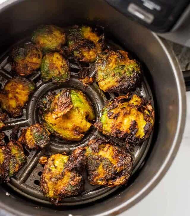 Air fryer basket filled with smashed brussel sprouts.