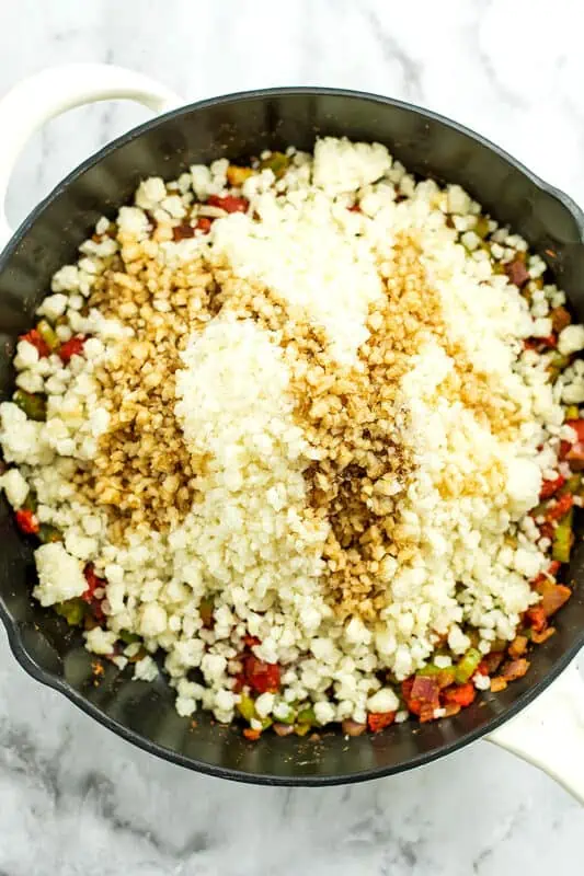 Frozen cauliflower rice and coconut aminos added to skillet. 