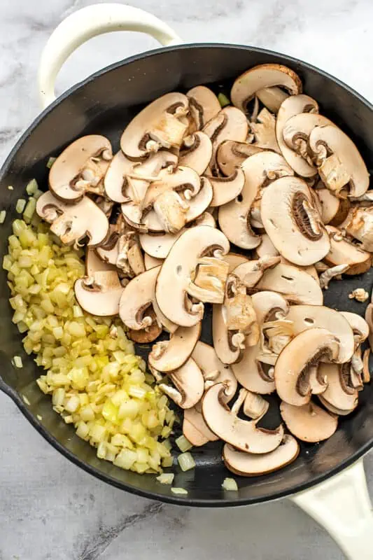 Sliced mushrooms and onions in a large skillet.