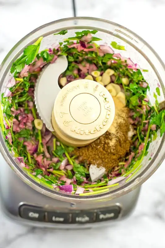 Spices added to onion and parsley mixture in food processor.