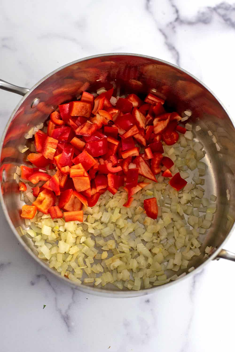 Fresh red bell peppers added to pot with cooked onions.