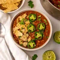 Lentil tortilla soup in a white bowl with cilantro and jalapeno on top.