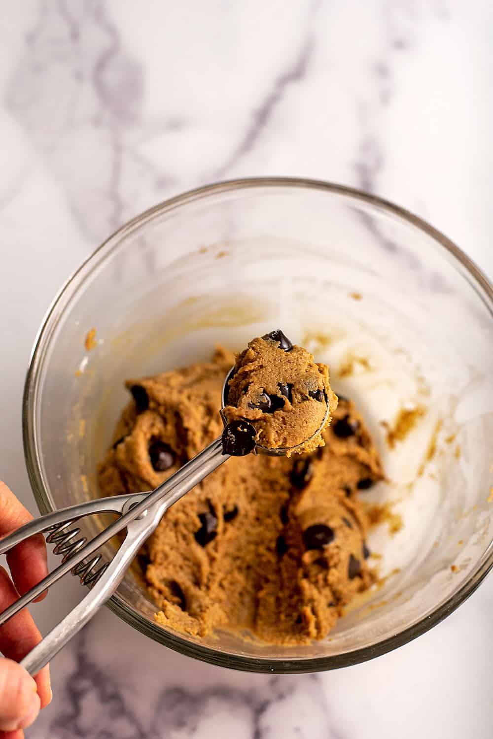 Cookie dough being scooped by a cookie scoop.
