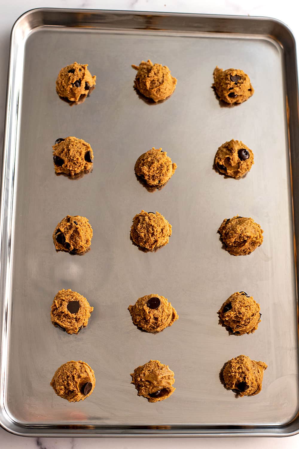 Chocolate chip oat flour cookie dough balls on baking sheet.