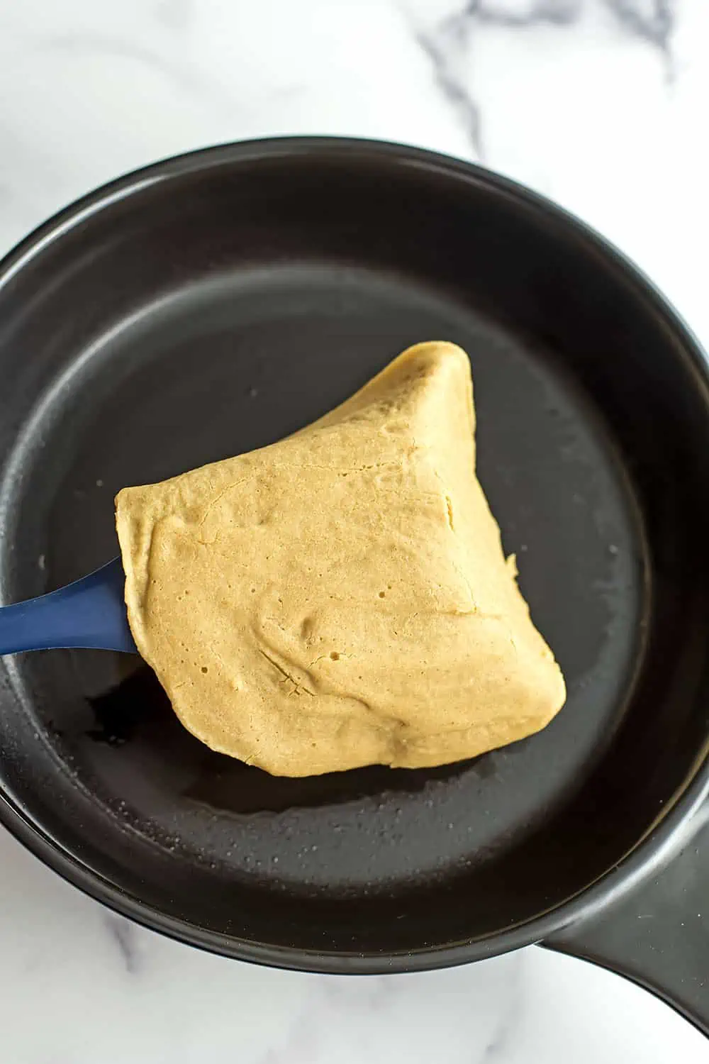 Blue spatula flipping oat flour tortilla.