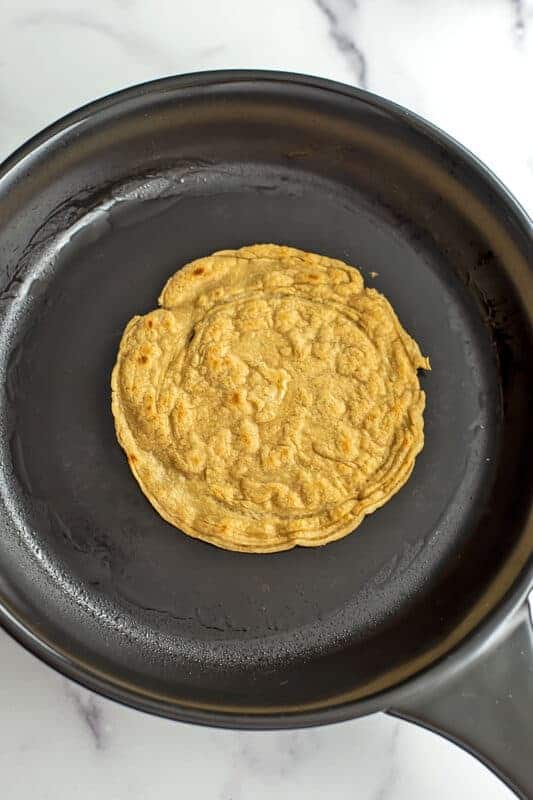 Oat tortilla after cooking in a large black skillet.