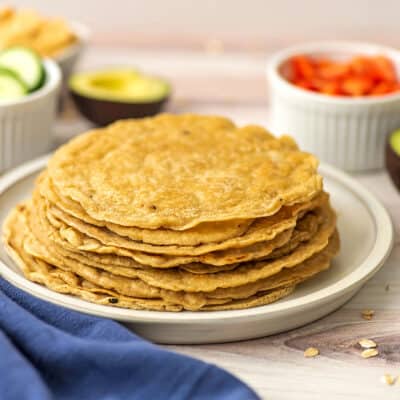 Oat tortillas stacked on a white plate, blue napkin in front.
