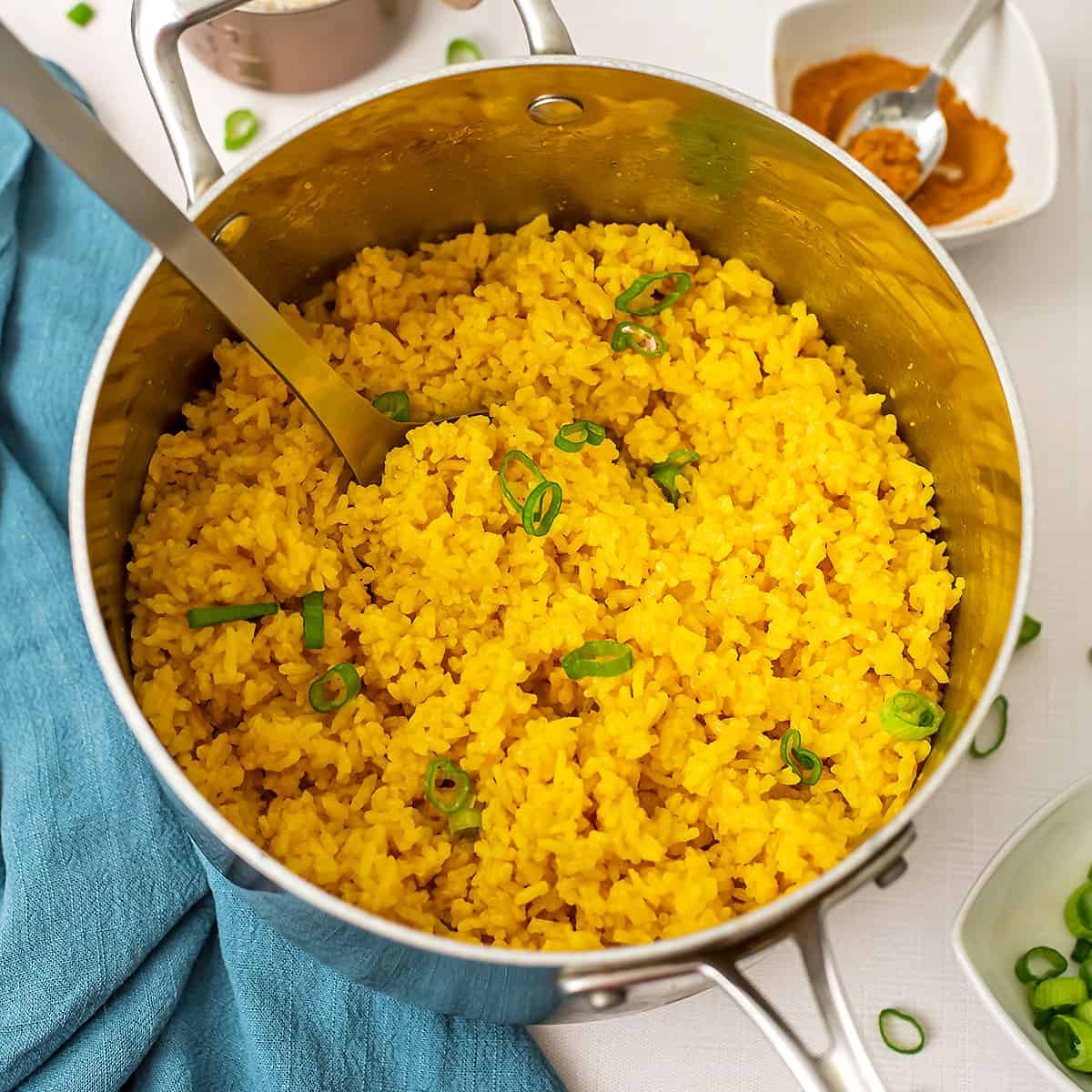 Pot filled with turmeric garlic rice with blue napkin on the side.