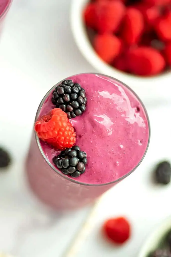 A blackberry raspberry smoothie overhead view with raspberry and blackberry fruit on top.