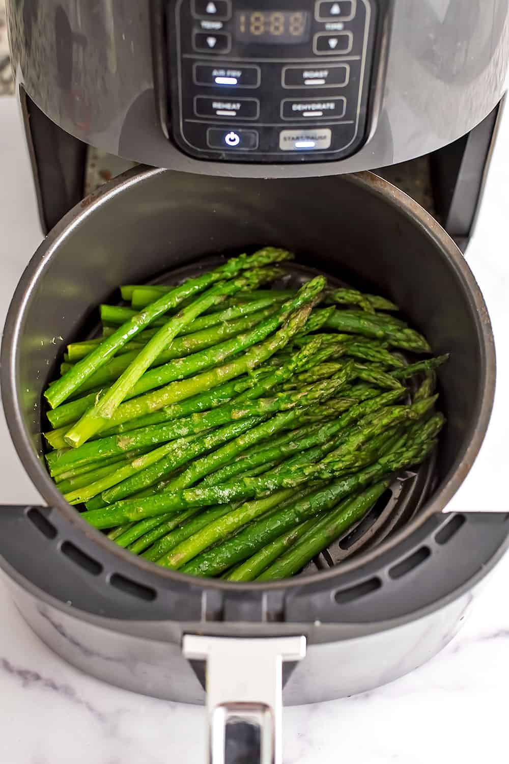 Frozen asparagus in air fryer half way through cooking.