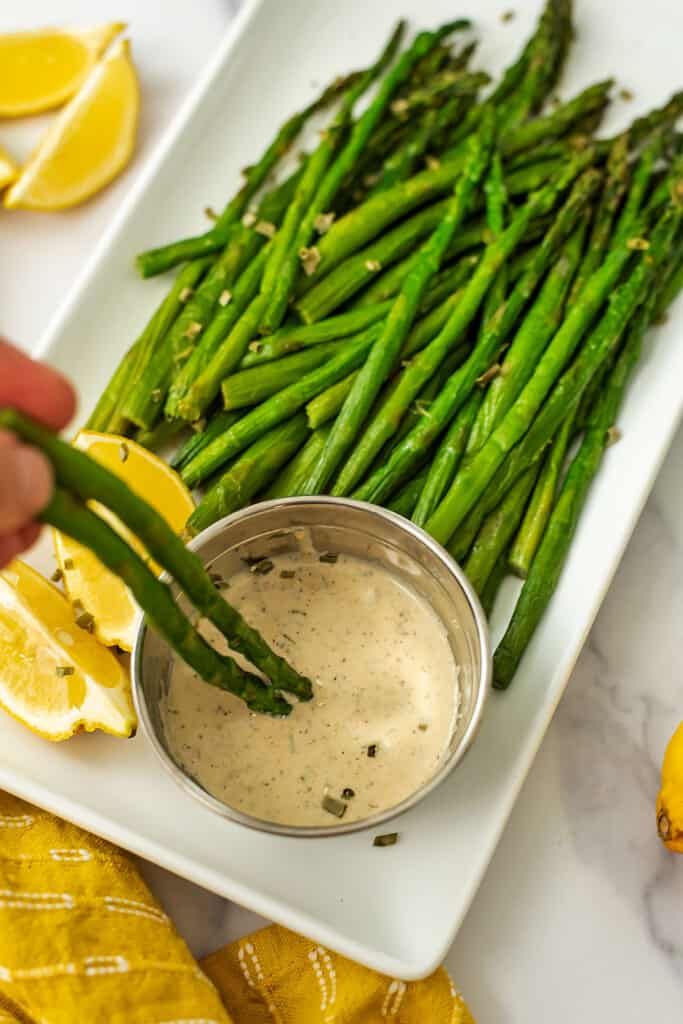 Two asparagus spears dipped in lemon tahini sauce.