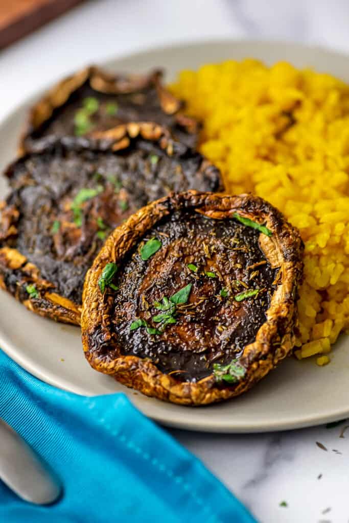 Air fryer portobello mushrooms on a plate with blue napkin on the side.